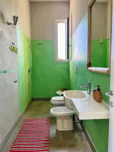 bagno verde con due servizi igienici e lavandino di Le Palombelle Casa Vacanze a Otranto