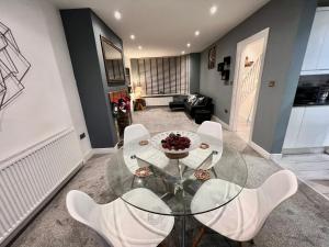 uma sala de jantar com uma mesa de vidro e cadeiras brancas em Opple house em Coventry