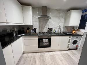 uma cozinha com armários brancos e um forno com placa de fogão em Cosy 3-bedroom house in Coventry by Seeka Stay, Ideal for contractors, Free parking on drive, Sleeps up 5 em Coventry