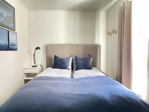 a bedroom with a large bed with blue pillows at High standard Lodge Ballstad in Ballstad