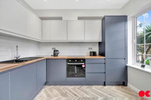 uma cozinha com armários brancos e um frigorífico azul em Entire 2 bed flat London Zone 1-4 with private garden em Londres
