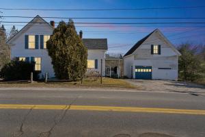 a white house on the side of a street at Serene Coastal Retreat home in Gouldsboro