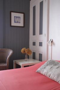 a bedroom with a red bed and a chair and a table at Hôtel Des Deux Mers in Saint-Pierre-Quiberon