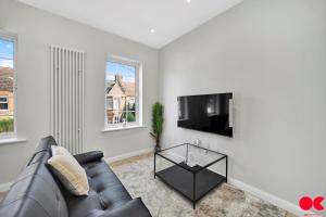 uma sala de estar com um sofá de couro preto e uma televisão de ecrã plano em Entire 2 bed flat London Zone 1-4 with private garden em Londres