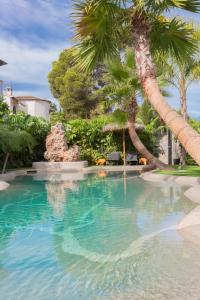 uma piscina com palmeiras num resort em Hotel Casa Lili em Xàbia