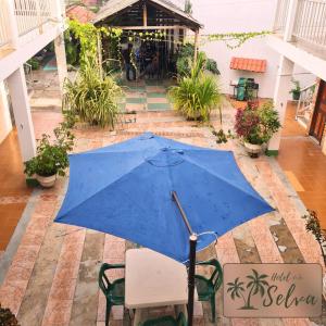 ein blauer Regenschirm auf einem Stuhl auf einer Terrasse in der Unterkunft Hotel de la Selva in Leticia