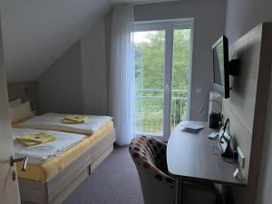 a bedroom with a bed and a desk and a window at Hotel am Steinertsee - Kassel-Ost in Kaufungen