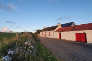 a building with a red door on the side of a road at Wild Atlantic Seaside Cottage in Easkey
