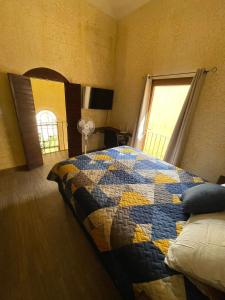 ein Schlafzimmer mit einer Decke auf einem Bett und einem Fenster in der Unterkunft Casa Santuario in Antigua Guatemala