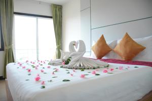 twee witte zwanen zitten op een bed met bloemen bij Zephyr Grand Hotel in Patong Beach