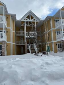 a large yellow building with snow in front of it at Valley Vista Haven - Exquisite Condo Retreat with Jacuzzi - Top Floor Romance - Self-Check-in - Gourmet Kitchen - Heated Pool Paradise in Shanty Bay