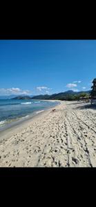 a beach with footprints in the sand and the water at Adriana Rinaldi Gonçalves in Angra dos Reis