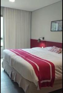 un grande letto con una coperta rossa e bianca sopra di Adriana Rinaldi Gonçalves ad Angra dos Reis