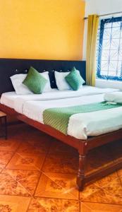 a bedroom with a bed with green and white pillows at Baga Beach Paradise in Baga