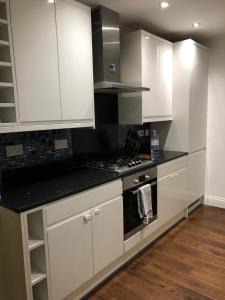 a kitchen with white cabinets and a stove top oven at Mill Hill Modern 3 Bedroom Apartment in Mill Hill
