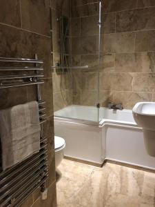 a bathroom with a tub and a toilet and a sink at Mill Hill Modern 3 Bedroom Apartment in Mill Hill