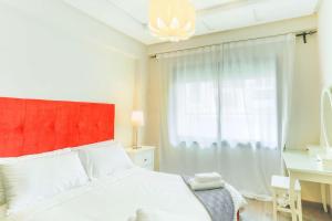 sypialnia z łóżkiem z czerwonym zagłówkiem i oknem w obiekcie Résidence Massira Square Place w mieście Casablanca