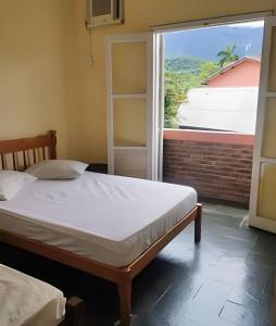 a bedroom with a bed and a large window at Chalés Caraguá Massaguaçu in Caraguatatuba