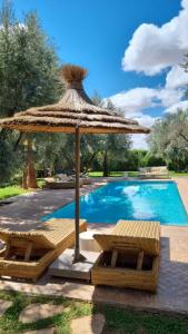 a large straw umbrella and chairs next to a swimming pool at VILLA PASCHMINA PISCINE CHAUFFEE in Ourika