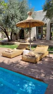 two beds with an umbrella next to a pool at VILLA PASCHMINA PISCINE CHAUFFEE in Ourika