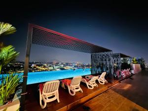 a deck with chairs and a swimming pool at night at Ipoh Horizon Skypool Town Suites 4-11pax by IWH Suites in Ipoh