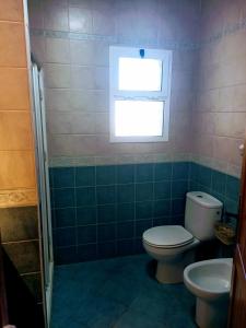 Un baño con inodoro y ventana. en Habitación acogedora y sencilla, en El Puerto de Santa María
