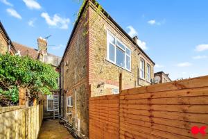 a brick house with a wooden fence in front of it at Entire 2 bed flat London Zone 1-4 with private garden in London