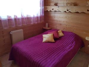 fioletowe łóżko w drewnianym pokoju z oknem w obiekcie Les Genévriers w mieście Foncine-le-Haut