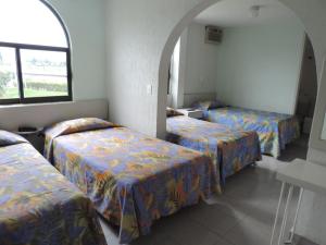 a room with three beds and a window at Dorados Conventions & Resort in Oaxtepec