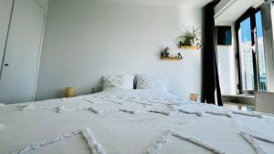 un letto bianco in una camera bianca con finestra di Montparnasse, 2 cozy private rooms in shared apartment a Parigi