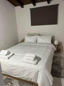 Una cama blanca con toallas encima. en The penthouse, en Maniákoi