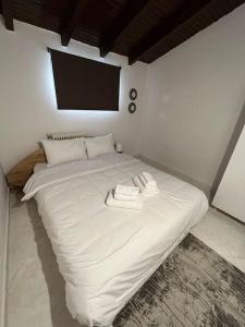 Una cama blanca con dos toallas encima. en The penthouse, en Maniákoi