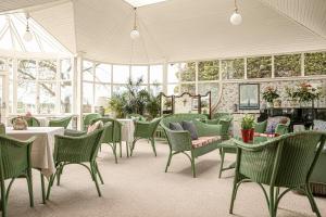 um quarto com cadeiras verdes, mesas e janelas em Kinloch House Hotel em Blairgowrie