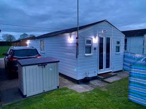 una pequeña casa azul con un coche aparcado al lado en All Seasons Chalet Breaks en Leysdown-on-Sea
