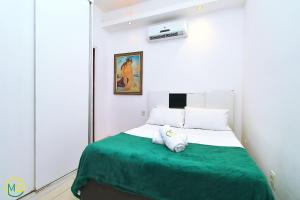 1 dormitorio con 1 cama con manta verde en Silencioso e aconchegante studio em Copacabana, en Río de Janeiro