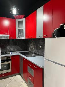 a red kitchen with white appliances and red cabinets at Bega's Apartment in Golem, Durrës in Golem