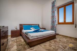 een slaapkamer met een bed met blauwe kussens en een raam bij Casa Vacanze Mare Dorato in Alcamo Marina