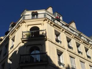 a white building with balconies and flowers on it at Bergère Opéra Trévise - 2 connecting rooms with private bathroom and 1 study room - 35 m2 in Paris