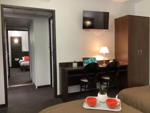 a hotel room with a desk and a bedroom at Hôtel Alliance in Lourdes