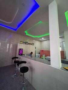 a bar with three stools in a room with purple lights at JF Royal Hotel & Suites in Ogbomoso