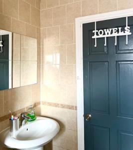 La salle de bains est pourvue d'un lavabo et d'une porte bleue. dans l'établissement 3 BDR House ,Free Parking ,Netflix ,WiFi, baby Cot upto 2yrs, à Manchester