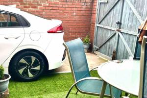 a white car parked next to a table and chairs at 3 Bedroom House Near Manchester City centre in Manchester