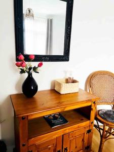 a table with a mirror and a vase with flowers on it at 3 Bedroom House Near Manchester City centre in Manchester