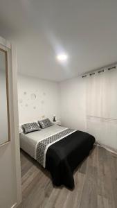 a bedroom with a bed with a black and white blanket at La de Fredyy - Tres Marias Apartments in Redondela