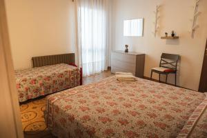 a hotel room with two beds and a chair at CasaDilva in Chioggia