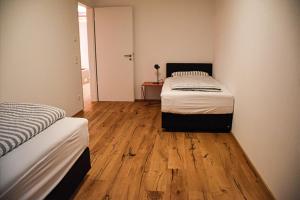 um quarto com 2 camas e piso em madeira em Ferienwohnung Bodenseeblick Nr 10 em Scheidegg