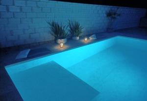 una piscina iluminada por la noche con luces en Habitación acogedora y sencilla, en El Puerto de Santa María