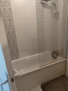 een wit bad met een glazen douchedeur bij Studio proche centre-ville et gare in Dax
