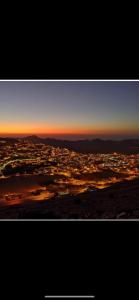 a view of a city with the sunset in the sky at Over Mountains Hotel in Wadi Musa