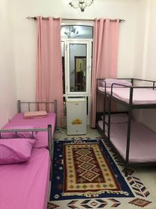 a room with three bunk beds with pink curtains and a rug at MOHAMMAD HOSTEL in Muscat